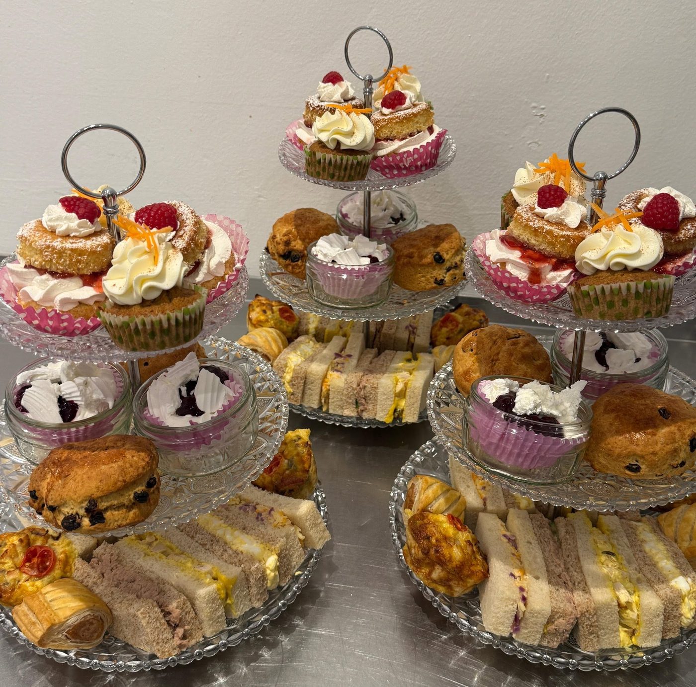 Three tiered cake stands of afternoon tea with sandwiches, scones and bite-sized cakes