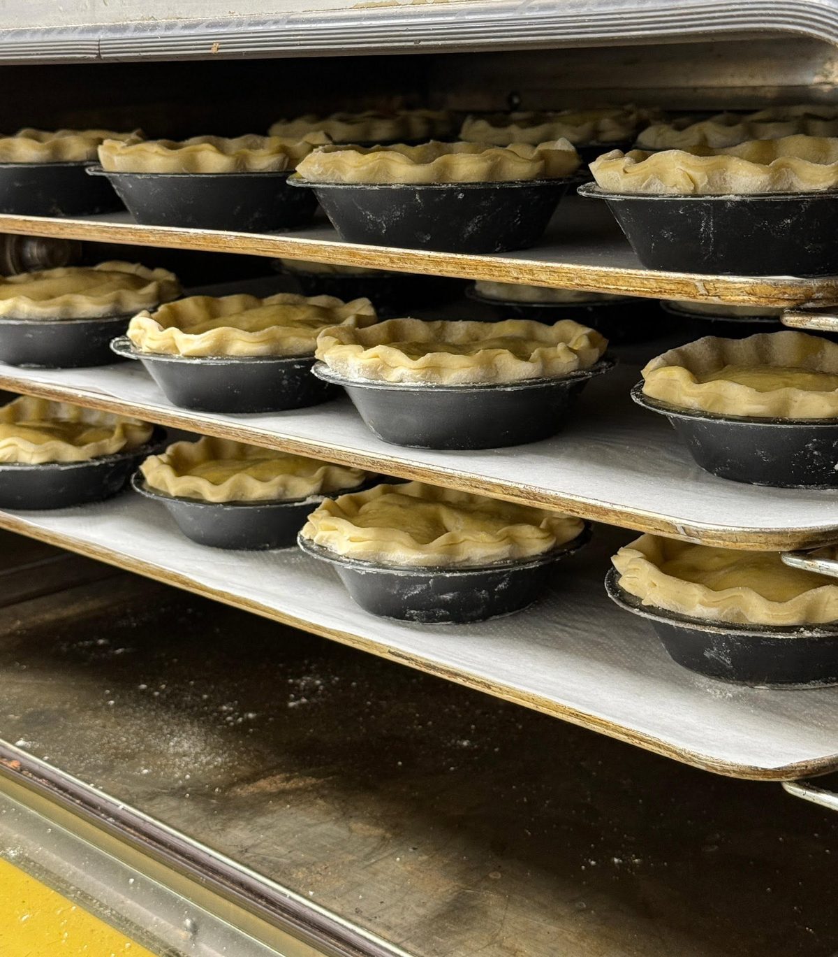 Unbaked pastry shells lined up on trays, ready for the oven