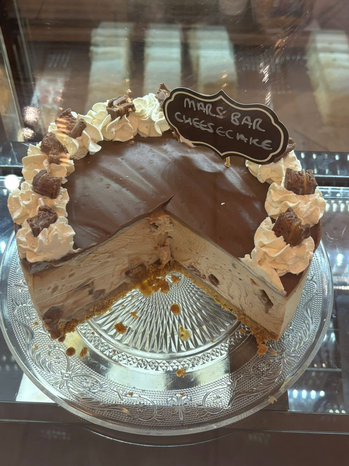 Mars Bar cheesecake, sliced, topped with chocolate ganache and whipped cream