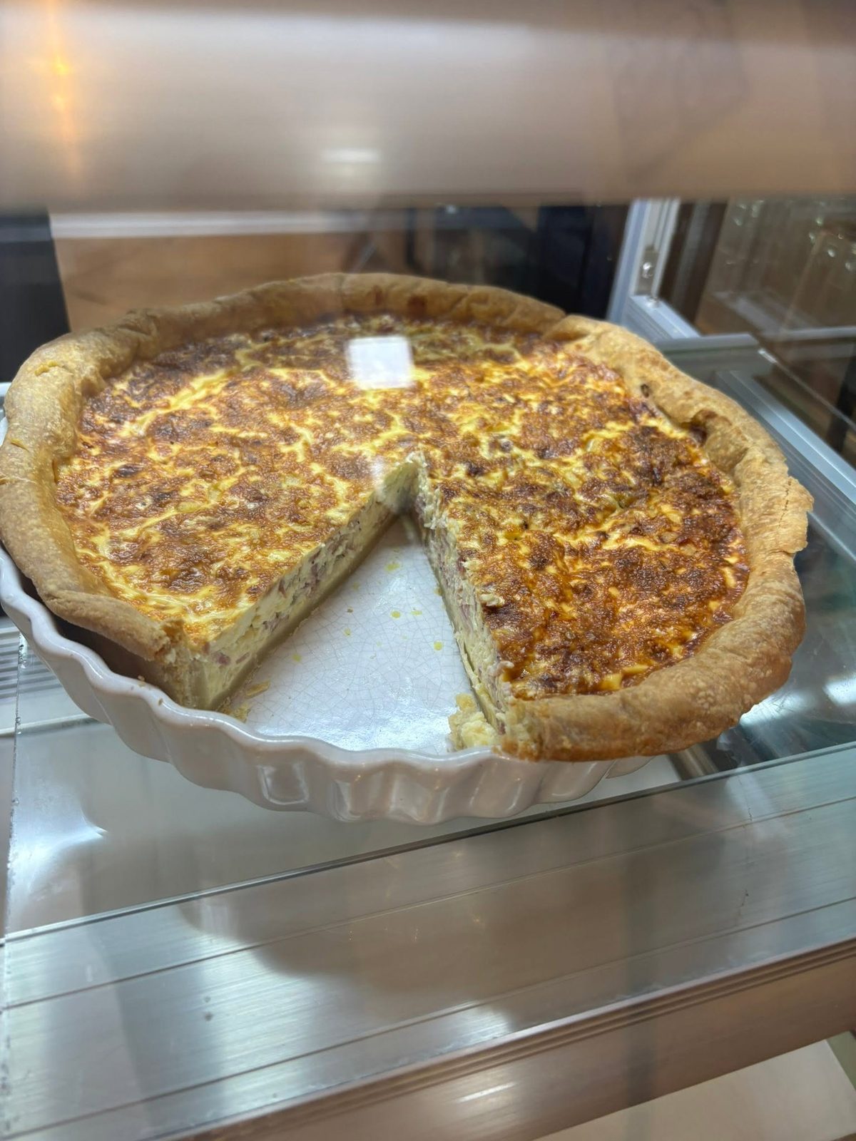 A golden baked quiche with a slice removed